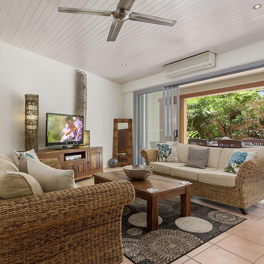 Living room of Mediterranean-style apartment with wicker sofas and a ground floor patio with lounge chairs and dining table