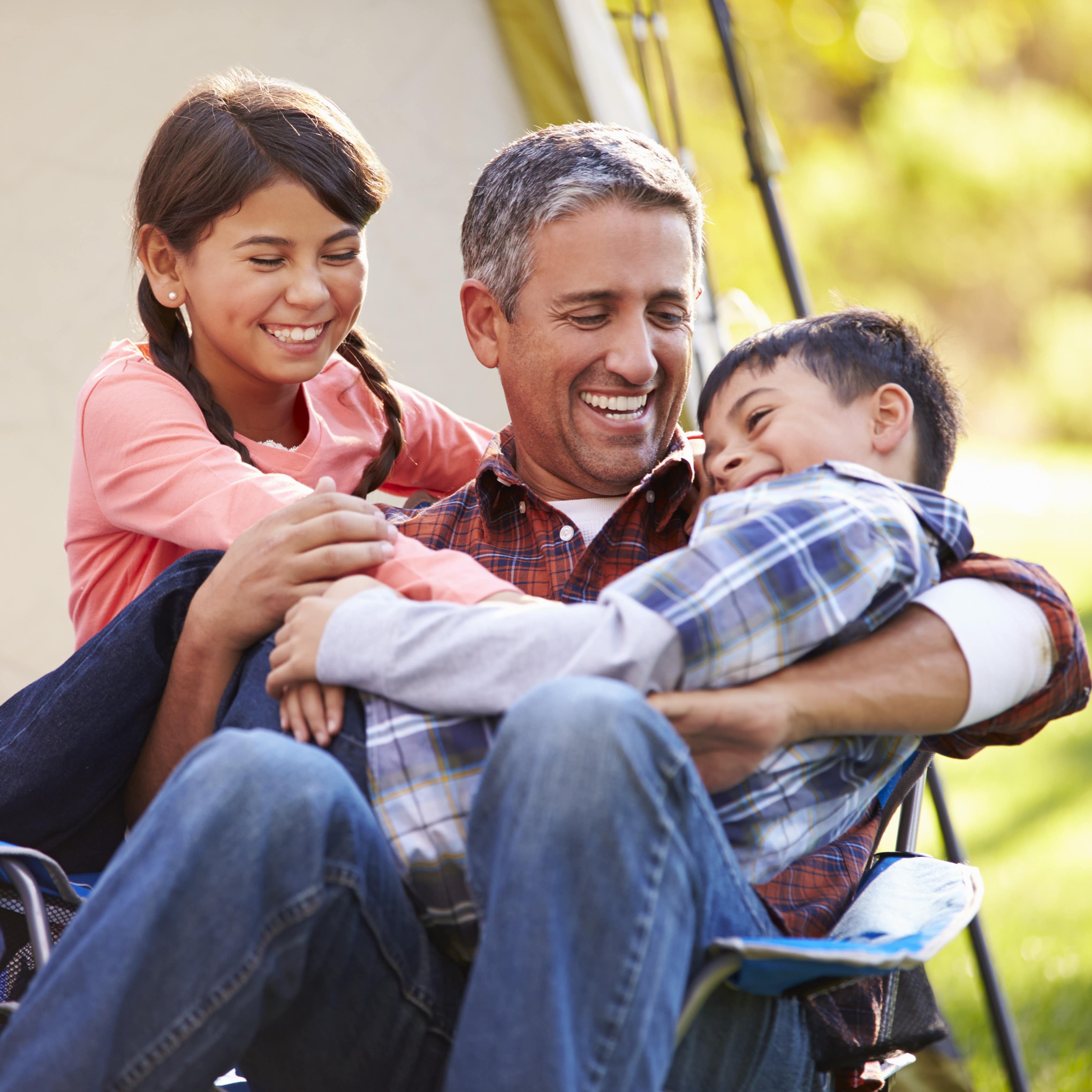 Father holding and enjoying children on camping trip