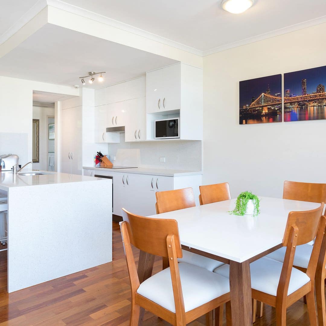 Modern dining room and kitchen, white walls, hardwood floors, contemporary dining set, white cabinets and kitchen island.