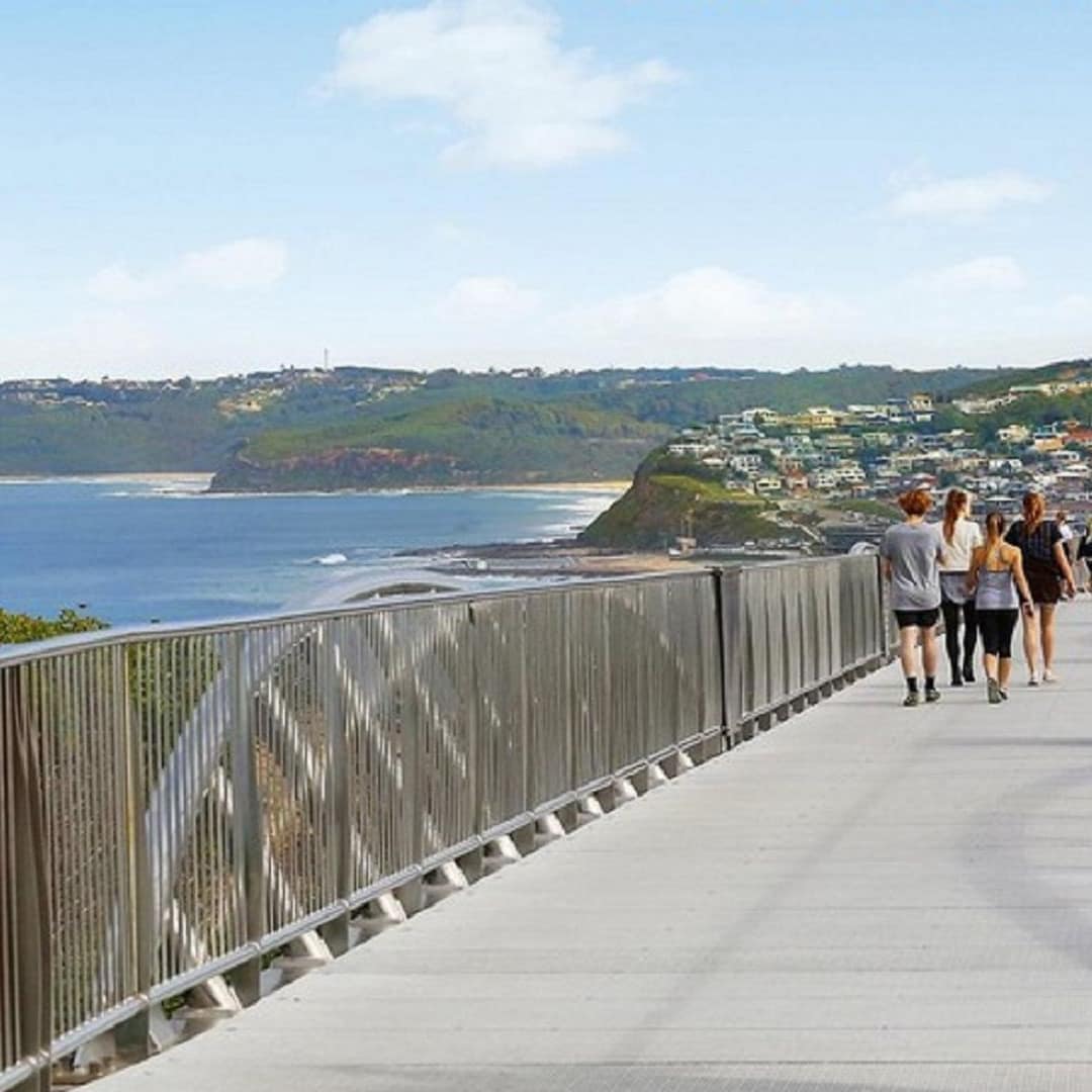 The Memorial Walk bridge with sea, mountains, and town in the background