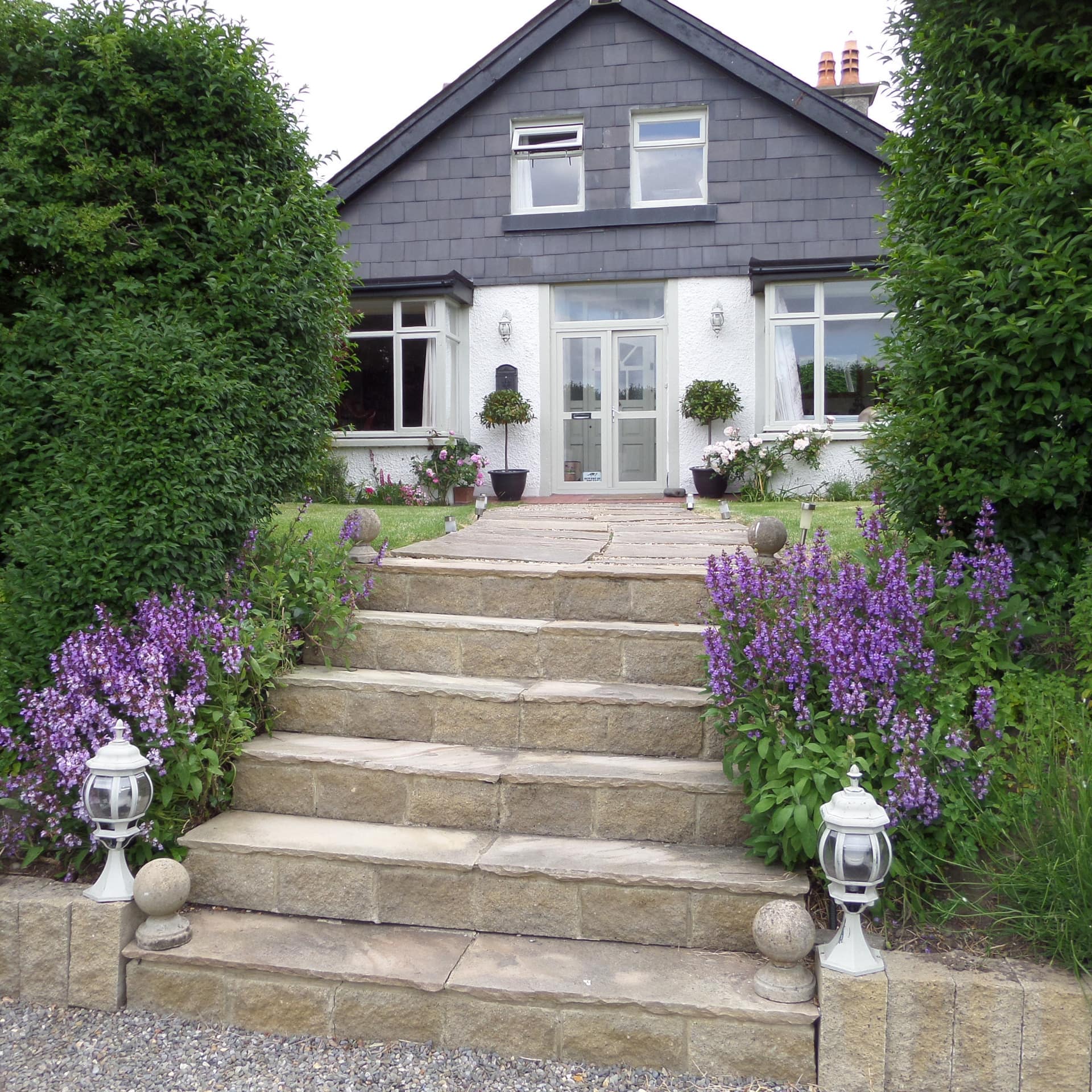 Historic 1921 B&B exterior with slate and white plaster walls, large windows and lovely front garden and limestone walk