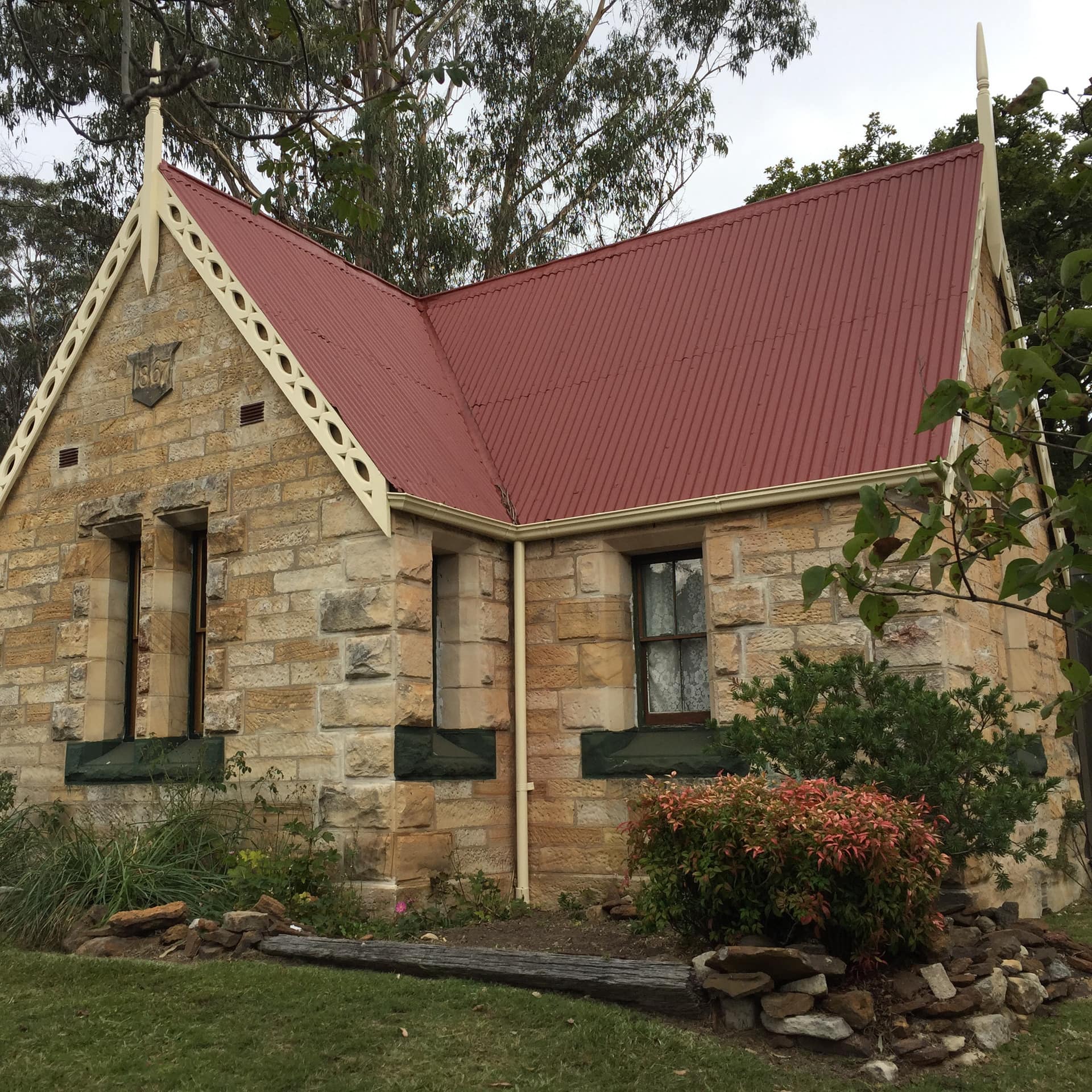 National Trust sandstone railway cottage with red roof and stone garden surrounded by trees