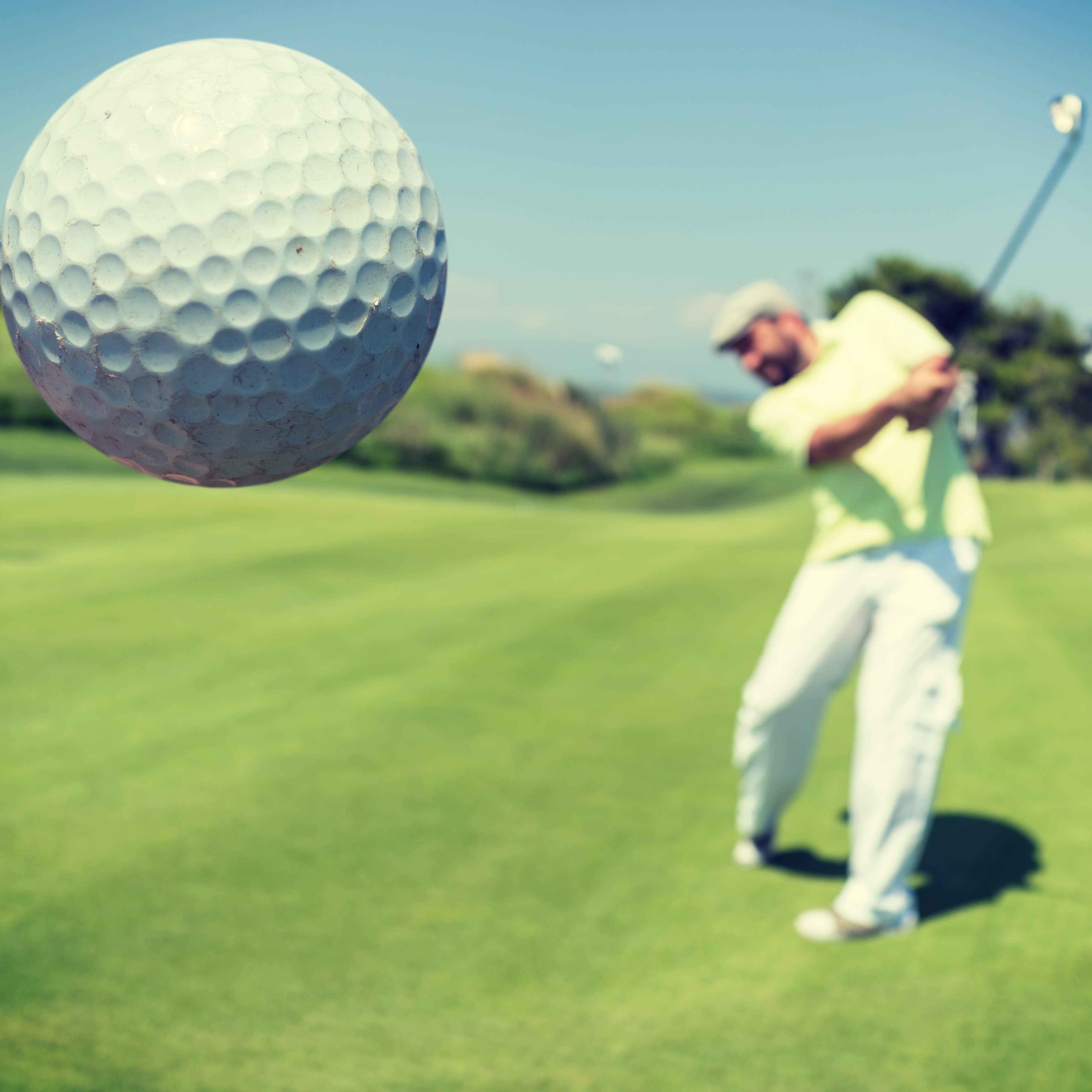Close up of golf ball with golfer in background