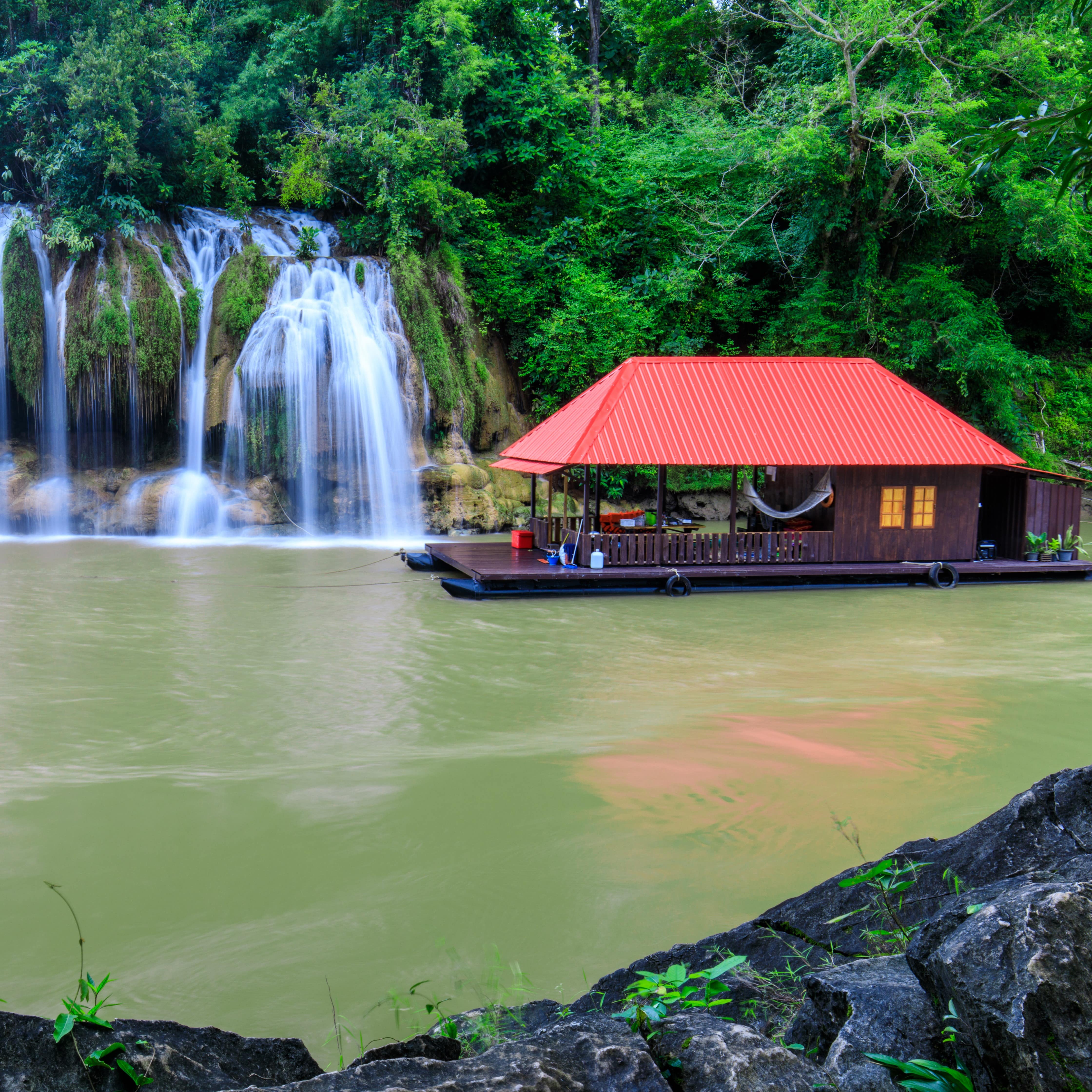 Waterfall in the jungle with a houseboat raft about to float in front of it