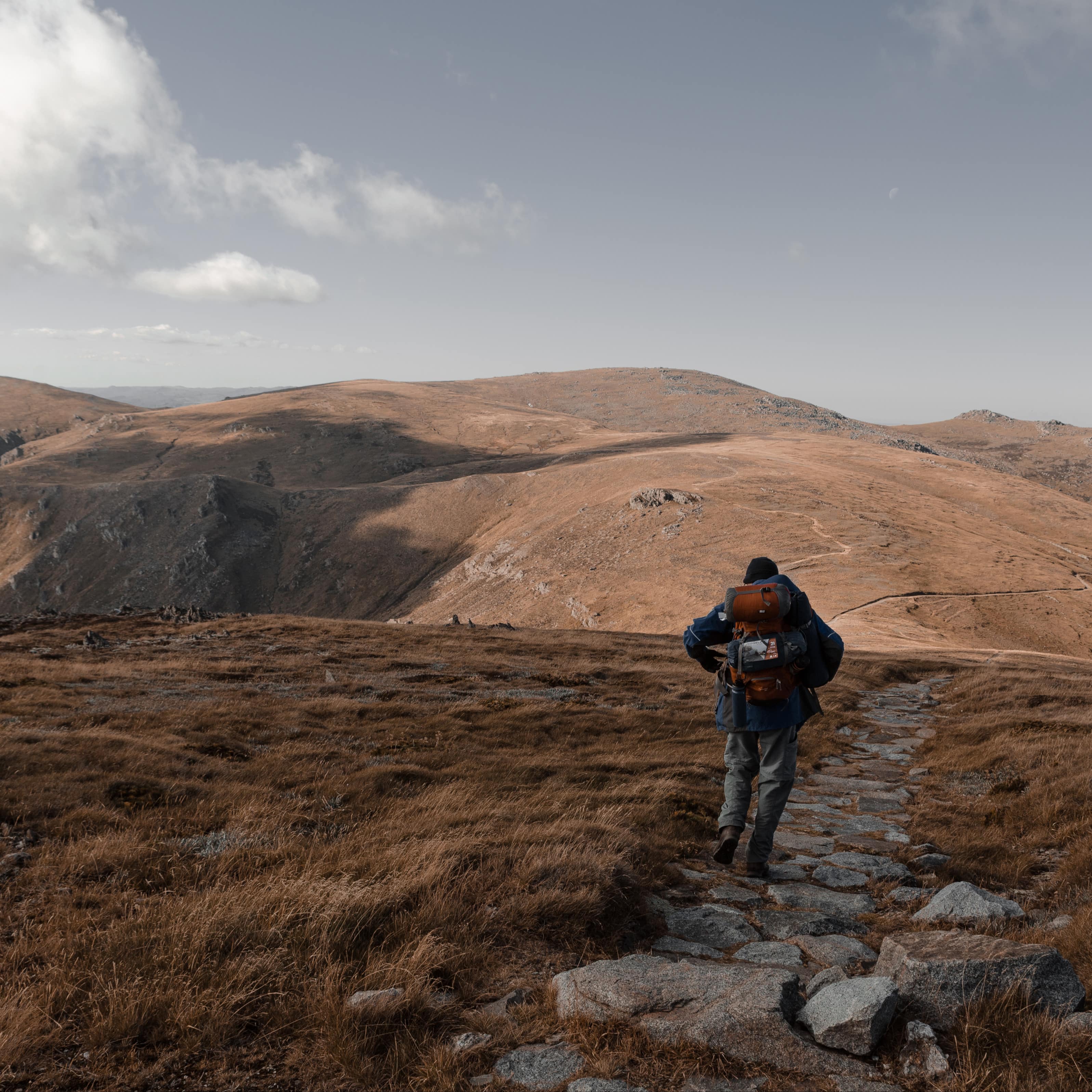 Man backpacking in the mountains in winter along a stone path