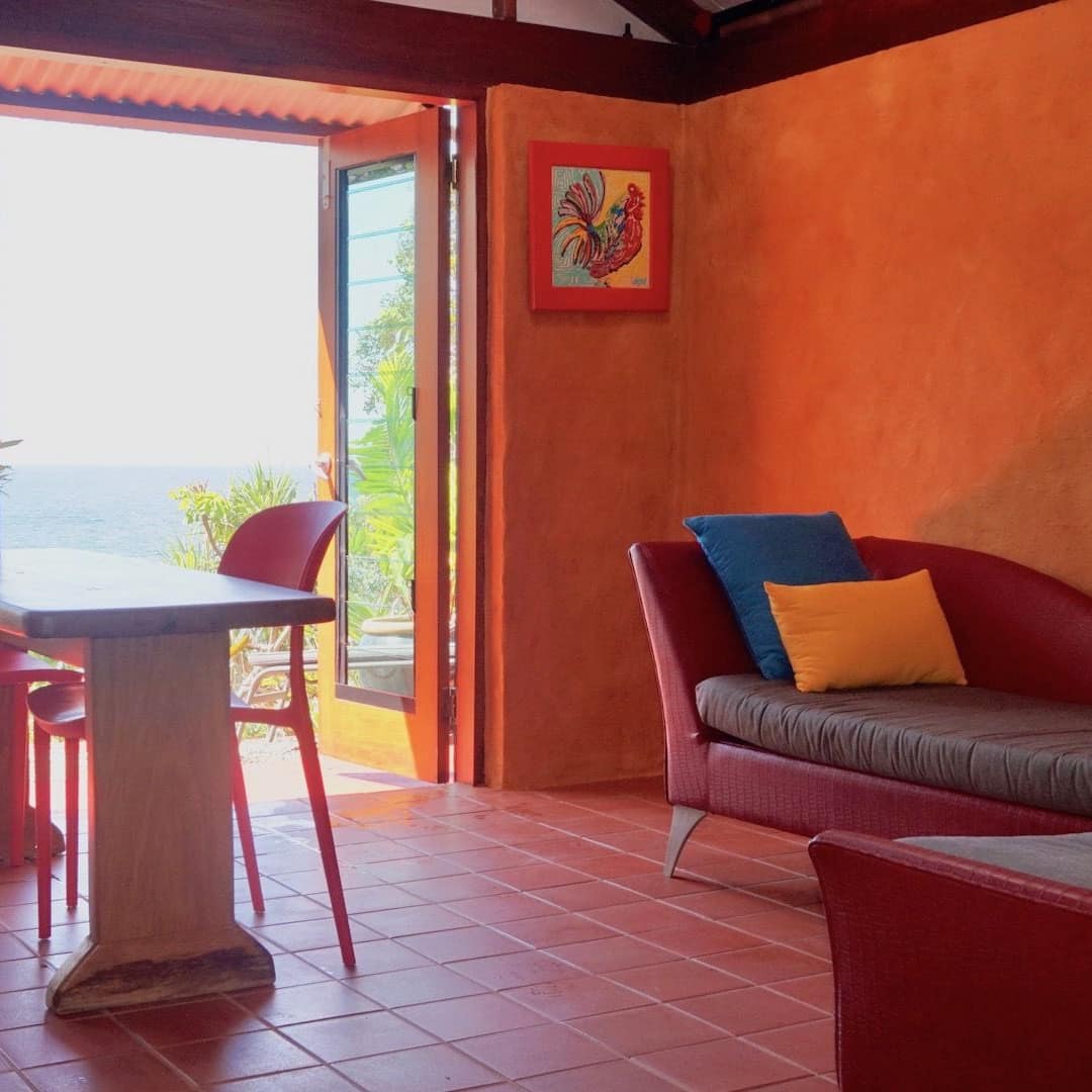 Bold living room and dining area of pet-friendly beach shack with chaise lounge and French doors opening to patio