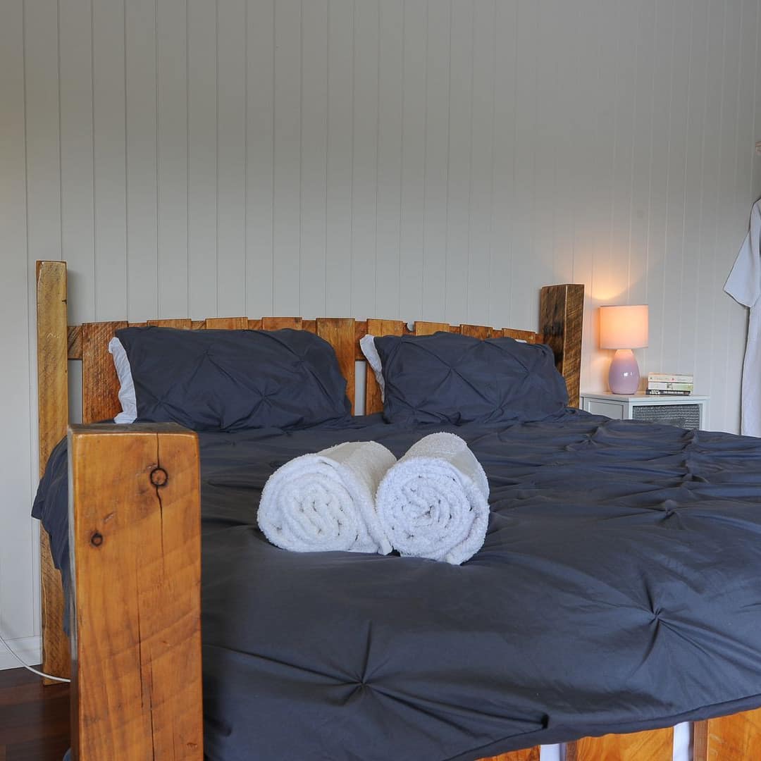 A rustic bedroom with white walls and a queen-sized bed