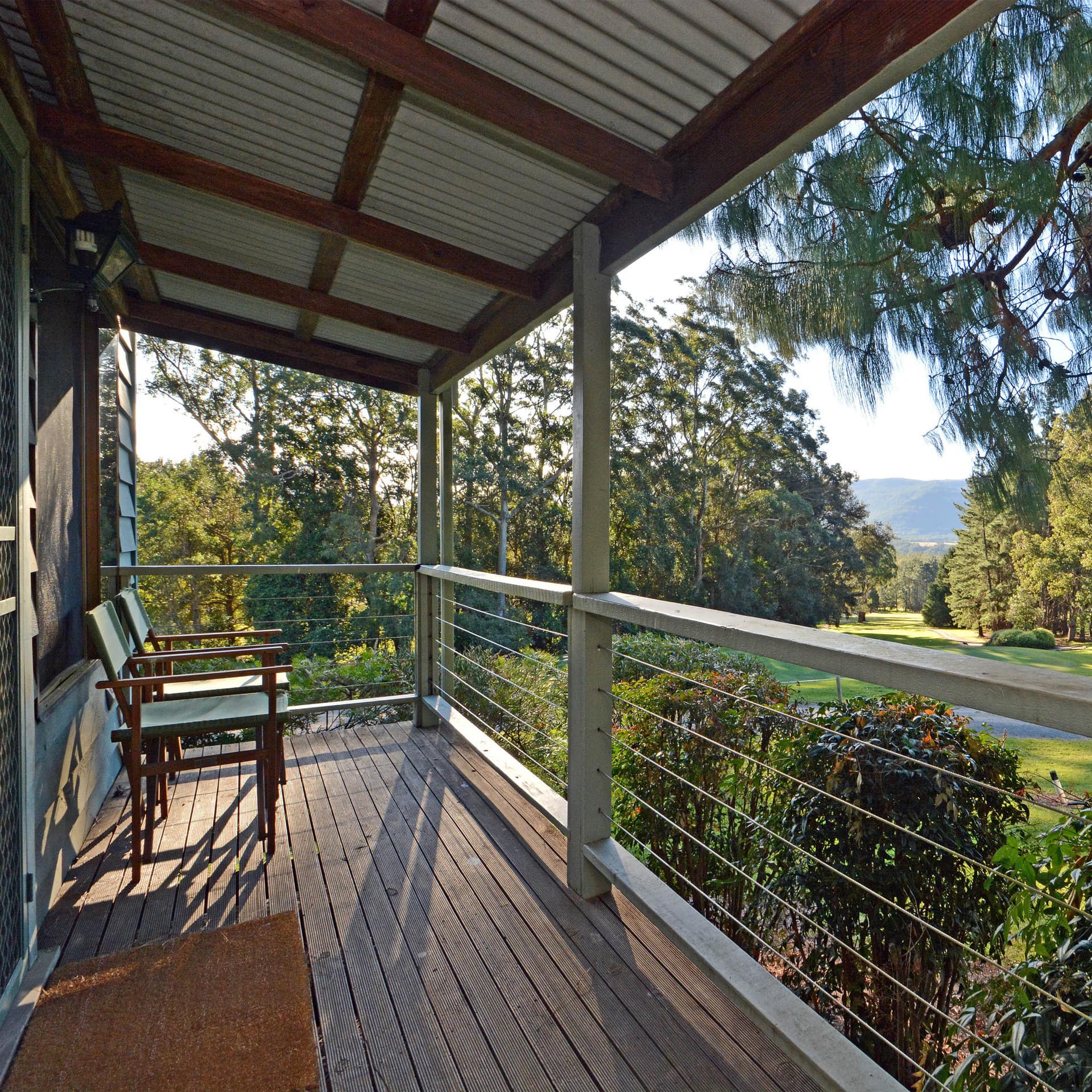 Minnamurra Rainforest cabin surrounded by plants and nature with porch overlooking trees