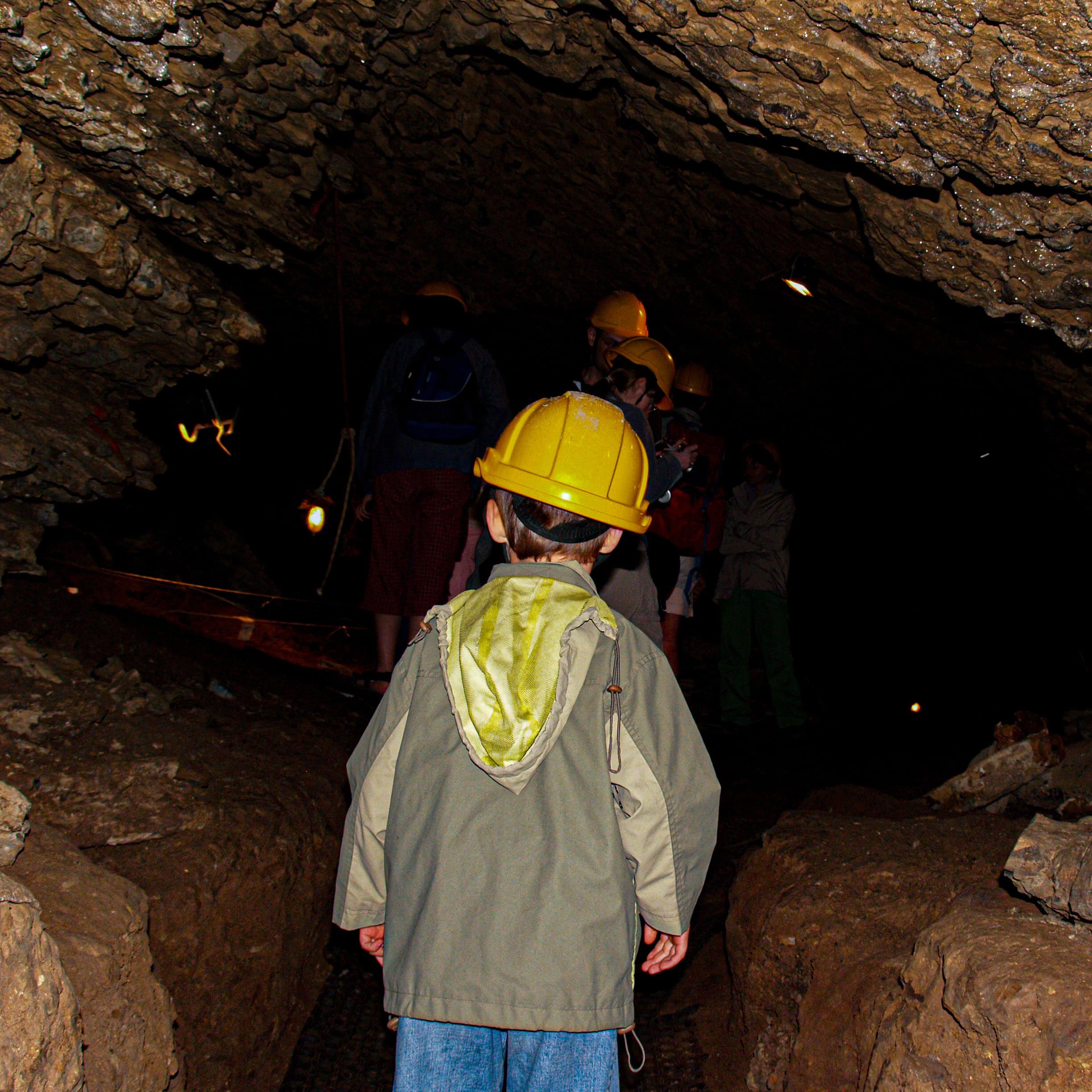 Young boy with yellow helmet exploring during cave tour