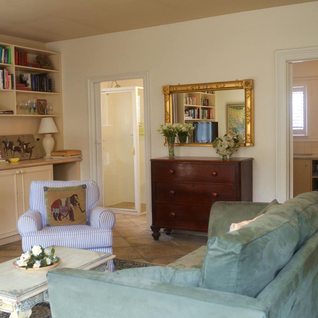 Comfortable B & B living room with sage-coloured sofa and chair, cream coffee table, bookshelf and antique chest