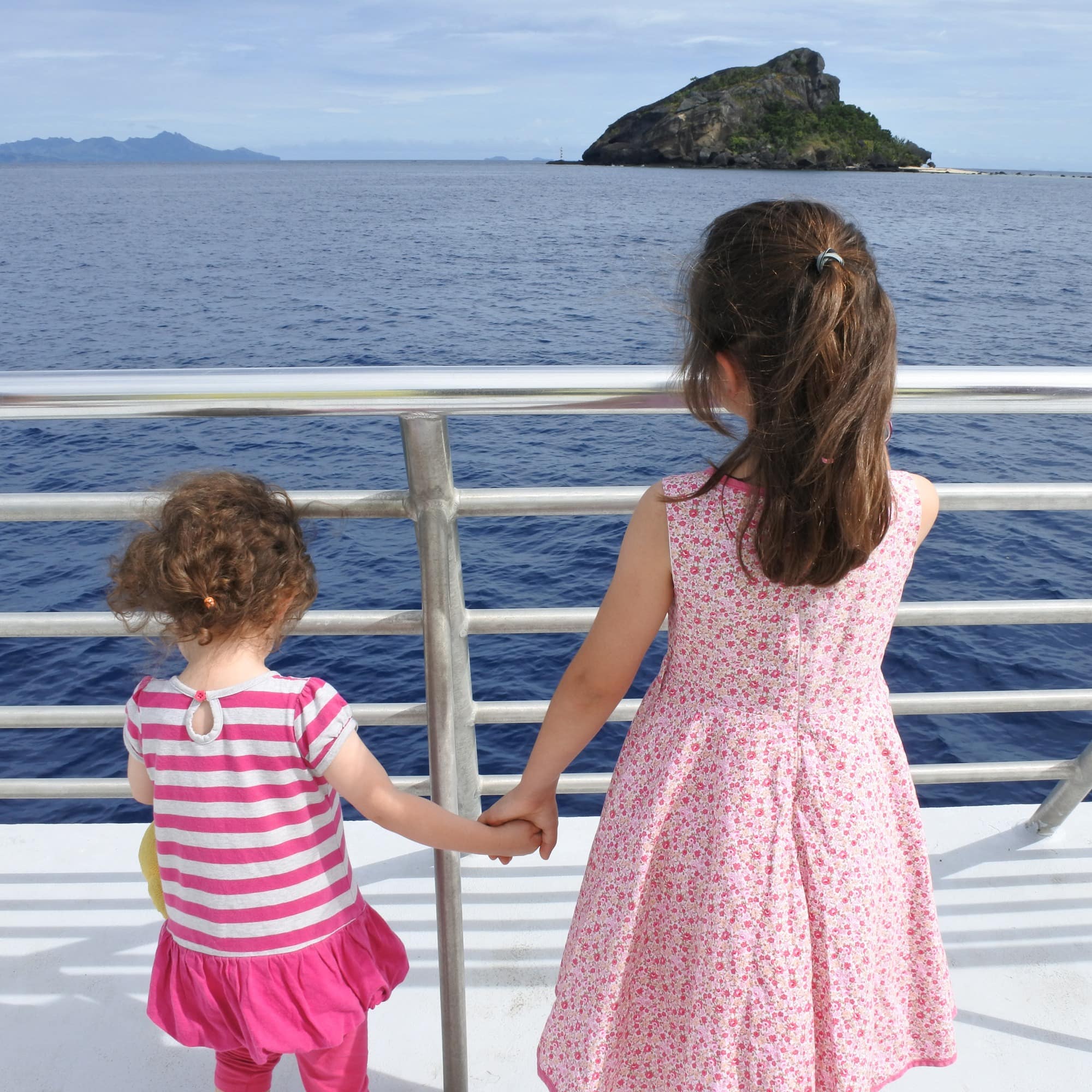 Two little girls in pink on boat looking out to the islands