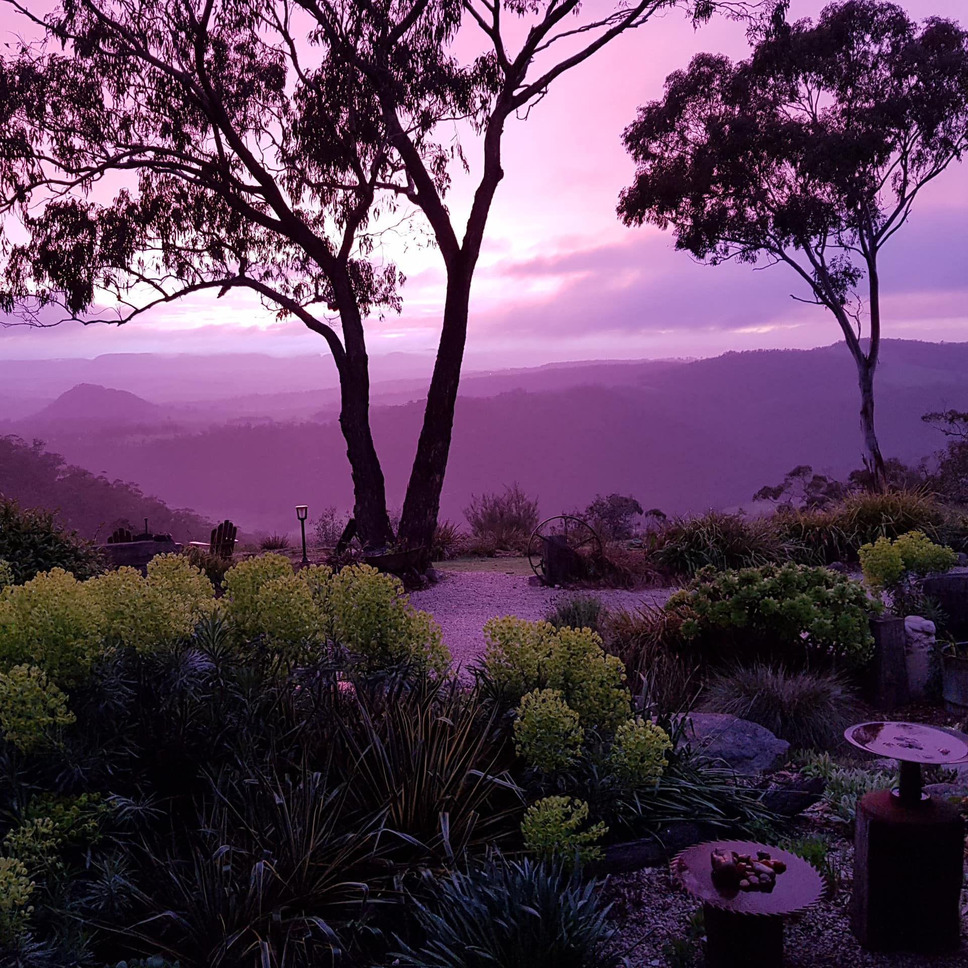 Cottage garden overlooking a purple mountain range with lavender skies at sunset