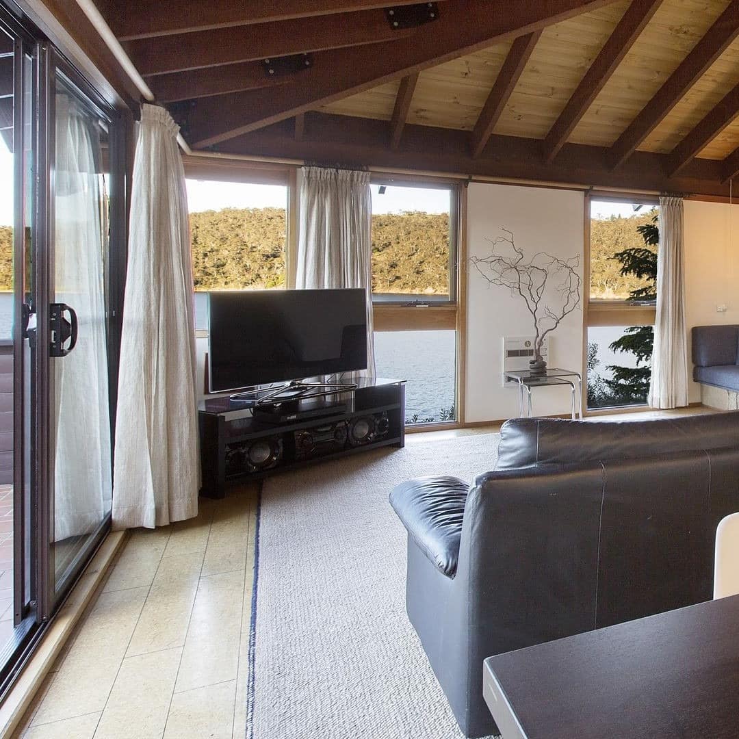 Cosy yet spacious living area with fireplace and large windows overlooking the calm lake